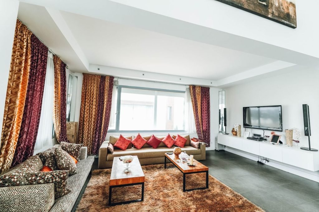 Bright and stylish living room featuring vibrant curtains and pillows, modern sofa, and home entertainment setup.